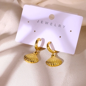 Détail de boucles d'oreilles créoles coquillage dorées sur une carte de bijoux