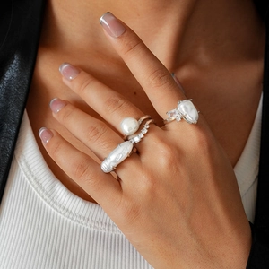 Macro shot of silver zircon rings with baroque pearls and textured layered details