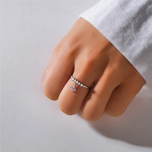 Close-up of S925 silver ring with five white diamonds and a pink clover petal charm
