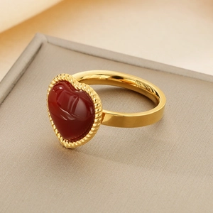 Dettaglio macro dell'anello a cuore con pietra rossa e bordo dorato a corda