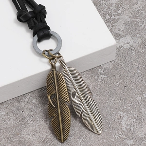 Close-up of bronze and silver alloy feather pendants on a black leather cord necklace