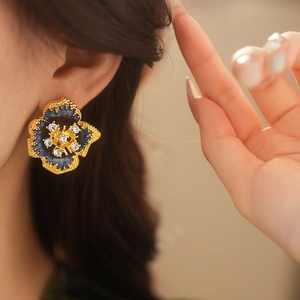 Close-up of vintage flower earring with dark blue petals and sparkling rhinestone center
