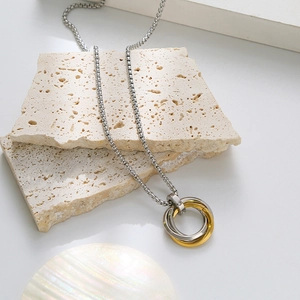 Three-ring interlocking pendant necklace in silver and gold tones on a white stone base