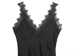 Detail of delicate eyelash lace trim on a black satin slip dress with silk-like finish