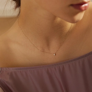 Close-up of minimalist S925 silver gold-plated necklace with a single pearl on a model