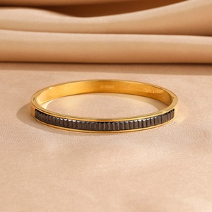 Detail of gold-plated stainless steel bracelet with pleated black textured inlay on silk