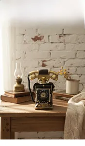 Close-up of vintage resin telephone model with antique finish on a rustic wooden desk