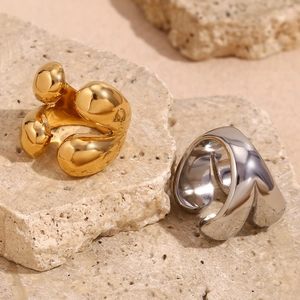 Détail de bagues gouttes d'eau en or 18 carats et argent sur fond de pierre beige