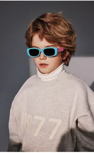 Young boy wearing polarized silicone sunglasses with light blue frames and purple temples