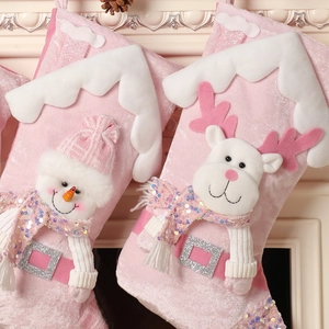 Pink sequined Christmas stockings with 3D snowman and reindeer decorations on a fireplace