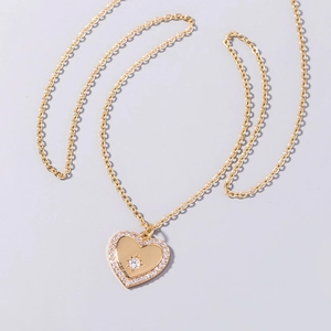 Close-up of golden heart pendant necklace with zircon crystals and minimalist fine chain