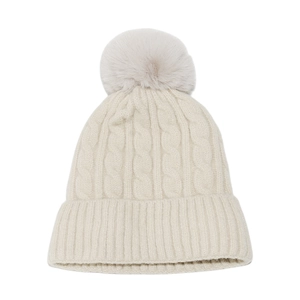 Détail d'un bonnet d'hiver en maille torsadée crème avec pompon en fourrure et revers