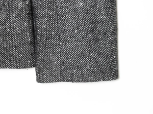 Detailed close-up of premium black and grey herringbone fabric texture on suit blazer