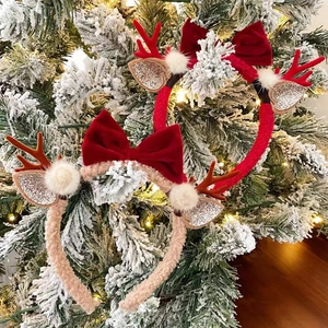 Detail of plush Christmas reindeer antlers headbands with bows on a snowy pine branch