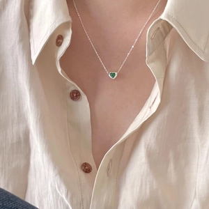 925 sterling silver necklace featuring a green heart-shaped gemstone on white shirt
