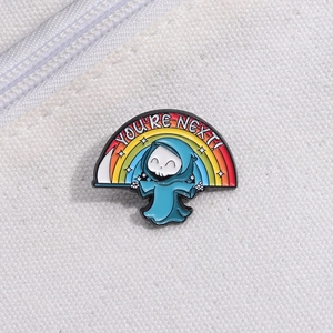 Dettaglio di una spilla smaltata reaper cartoon con arcobaleno su sfondo di tela bianca