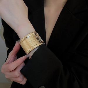 Macro shot of gold-plated statement cuff featuring a wide vertical ribbed texture