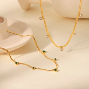 Detail of 18K gold snake chains featuring white and green bezel-set cubic zirconia