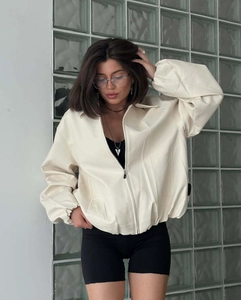 Detail of cream long-sleeve bomber jacket featuring metal zipper and smooth PU texture