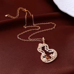 Detailed close-up of a gold hollow gourd necklace featuring a pearl and amber tiger eye stone
