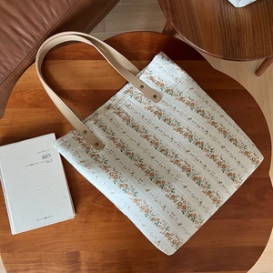 Sac fourre-tout en coton et lin à fleurs avec poignées en cuir sur une table en bois