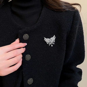Close-up of vintage butterfly brooch with pearls and tassels on black tweed coat
