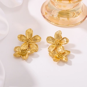 Golden double flower earrings with metallic texture on white silk background