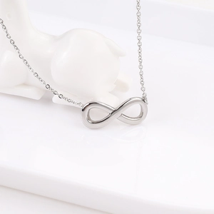 Primer plano del collar con colgante de infinito plateado en una bandeja blanca