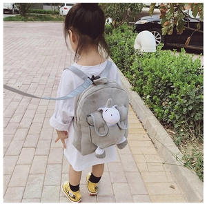 Outdoor shot of a toddler wearing a grey cartoon backpack with unicorn plush and safety leash
