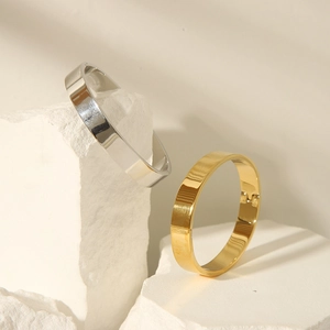 Close-up of gold and silver mirror polished bangles displayed on minimalist stones