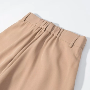 Detail view of khaki trousers showing elastic waistband, belt loops, and fine woven texture