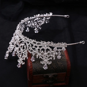 Detailed close-up of a silver baroque tiara with zircons on a vintage wooden box