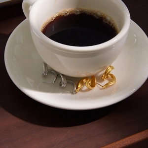Macro shot of 18K gold and silver plated twisted spiral hoop earrings on a coffee cup