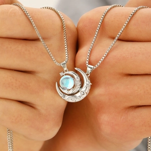 Close-up of magnetic sun and moon necklaces with blue stones on hand