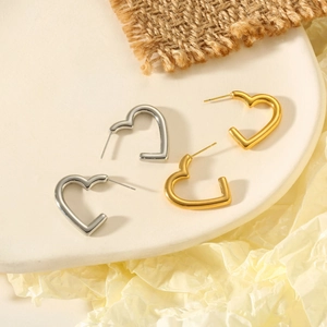 Vue de dessus des boucles d'oreilles cœur dorées et argentées sur un plateau en céramique