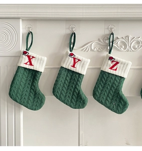 Detailed knit texture of green Christmas stockings with embroidered letters on white cuff