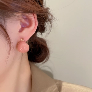Close-up of a pink enamel water drop earring with gold plating worn by a model