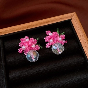 Detail of pink beaded flower earrings with green leaves and a clear faceted crystal drop