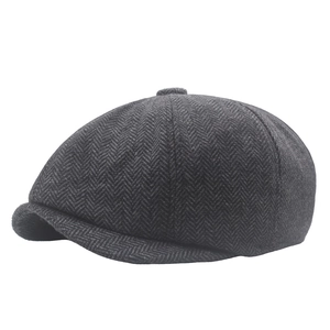 Detailed view of dark grey herringbone texture on a vintage style newsboy flat cap
