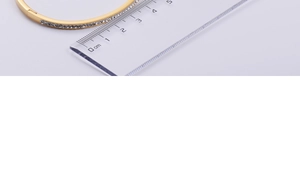 Detail shot measuring the inner diameter of the gold zircon bangle with a metric ruler