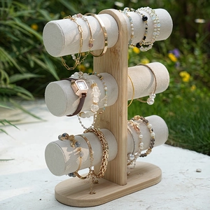 Three-tier bamboo jewelry display stand with beige velvet bars in outdoor setting