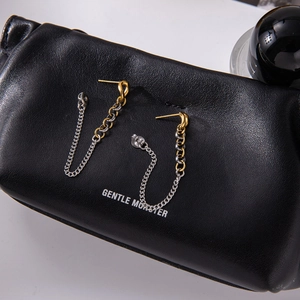 Vue macro des boucles d'oreilles bicolores dorées et argentées sur cuir noir