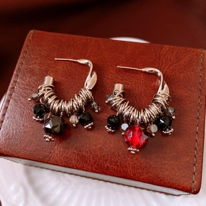 Detail of silver C-hoop earrings with vintage glass tassels on leather jewelry box