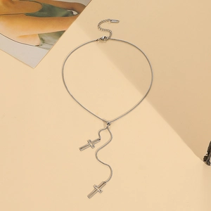 Detail of silver box chain necklace featuring two hollow cross pendants on beige background