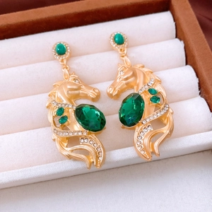 Gros plan détaillé de boucles d'oreilles cheval vintage avec cristaux verts et strass