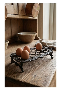 Detailopname van vintage gietijzeren eierhouder met 6 vakken op een rustieke houten tafel