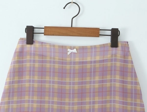 Close-up of checkered plaid skirt with a white bow tie detail on the waistband