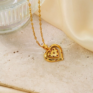 Elegant gold heart pendant necklace featuring red ruby stones on a silk fabric background