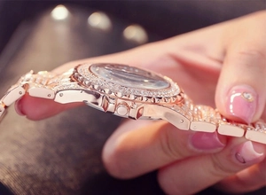 Nahaufnahme der roségoldenen, kristallbesetzten Lünette und des Metallarmbands der Damenuhr