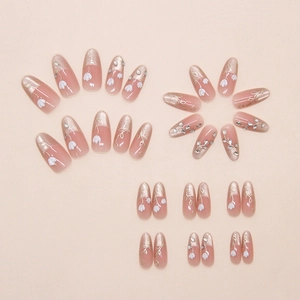 Detailed macro view of almond-shaped press-on nails with floral art and rhinestones